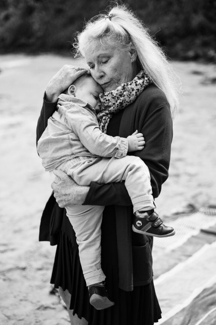 photo d'une grand-mère qui fait un câlin à son petit fils sur une plage