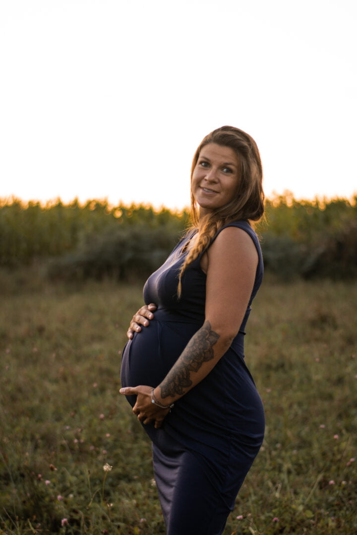 Femme souriante avec les mains sur son ventre durant sa grossesse