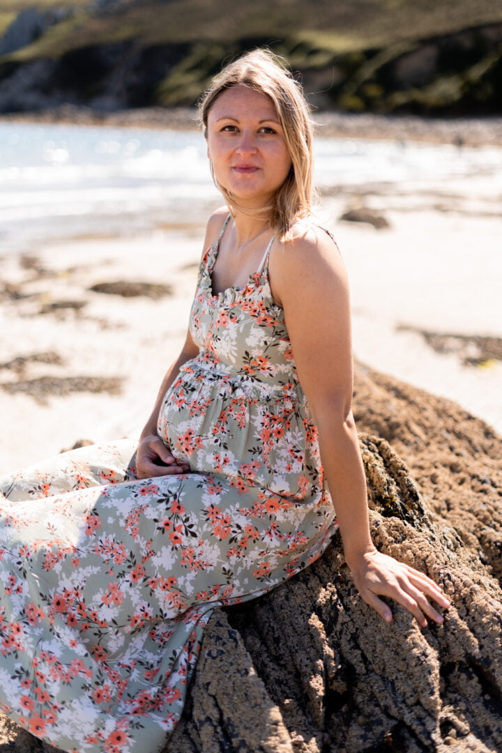 portrait d'une femme enceinte assise sur un rocher sur une plage de crozon