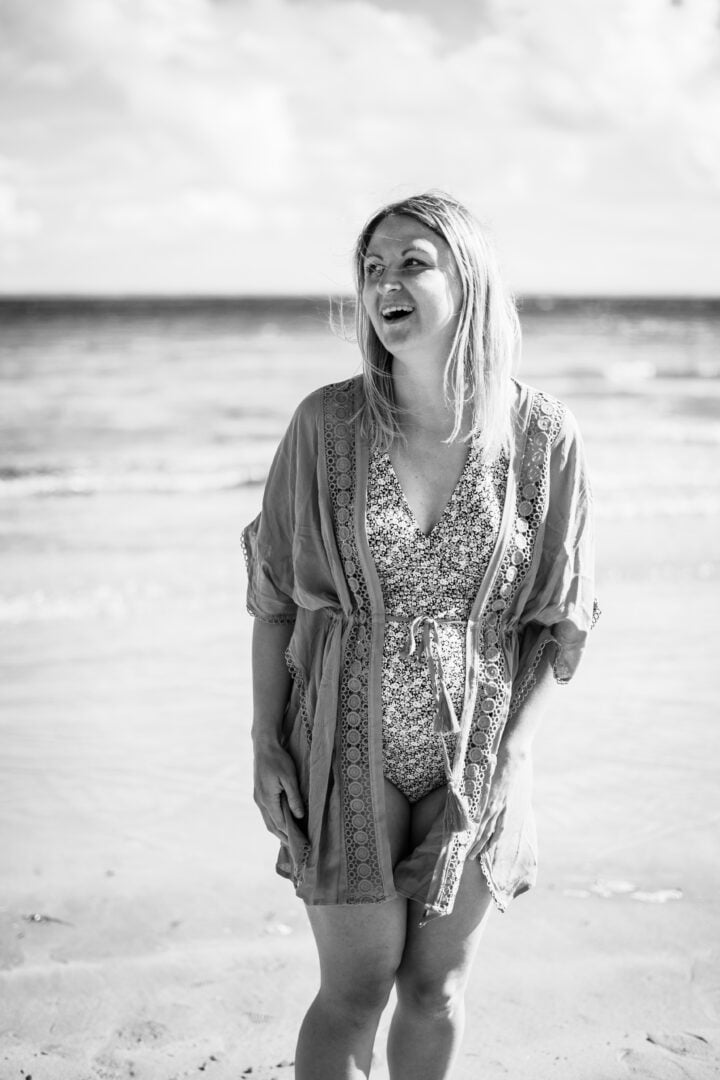 Photo en noir et blanc d'une femme enceinte qui rigole sur une plage