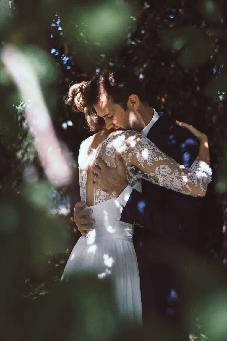 photo d'une couple qui s'enlace sous un arbre lors de leur mariage