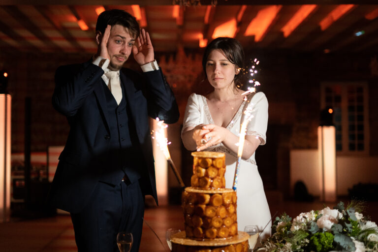 photo d'une mariée qui coupe la pièce montée à rennes et son mari effrayé à ses côtés