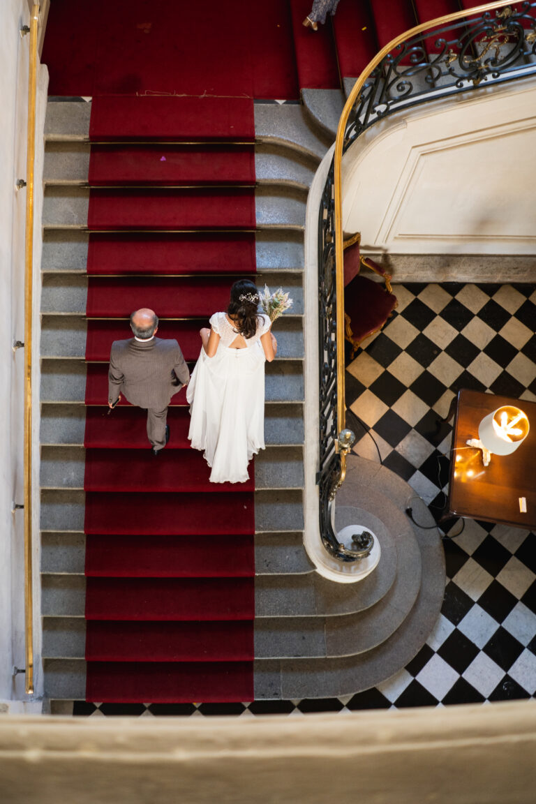 photo d'une mariée au bras de son père qui montent les escalier de la mairie de rennes