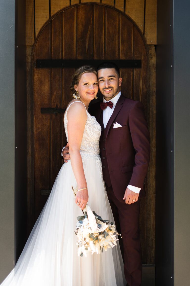 photo d'un couple heureux lors de leur mariage et qui pose devant une vieille porte en bois à rennes