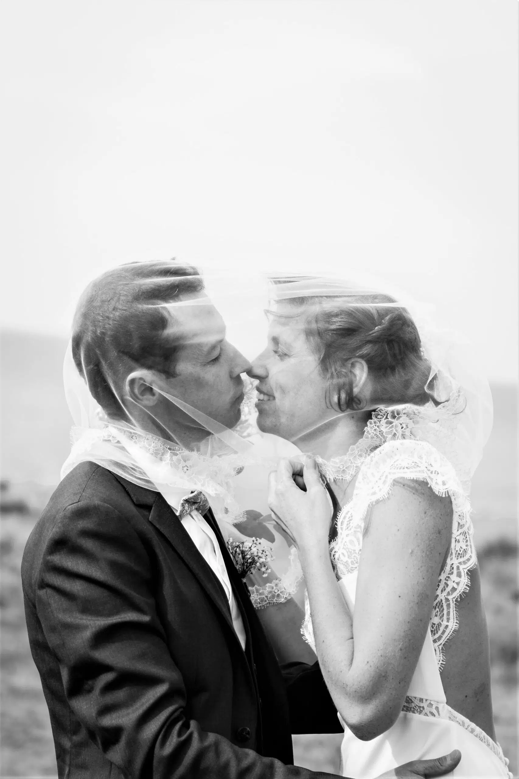 photo d'un couple qui s'embrasse sous le voile de la mariée lors de leur mariage