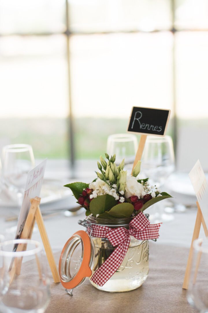 Décoration de table avec fleurs rouges et bocaux en verre - Mariage au Château des Pères