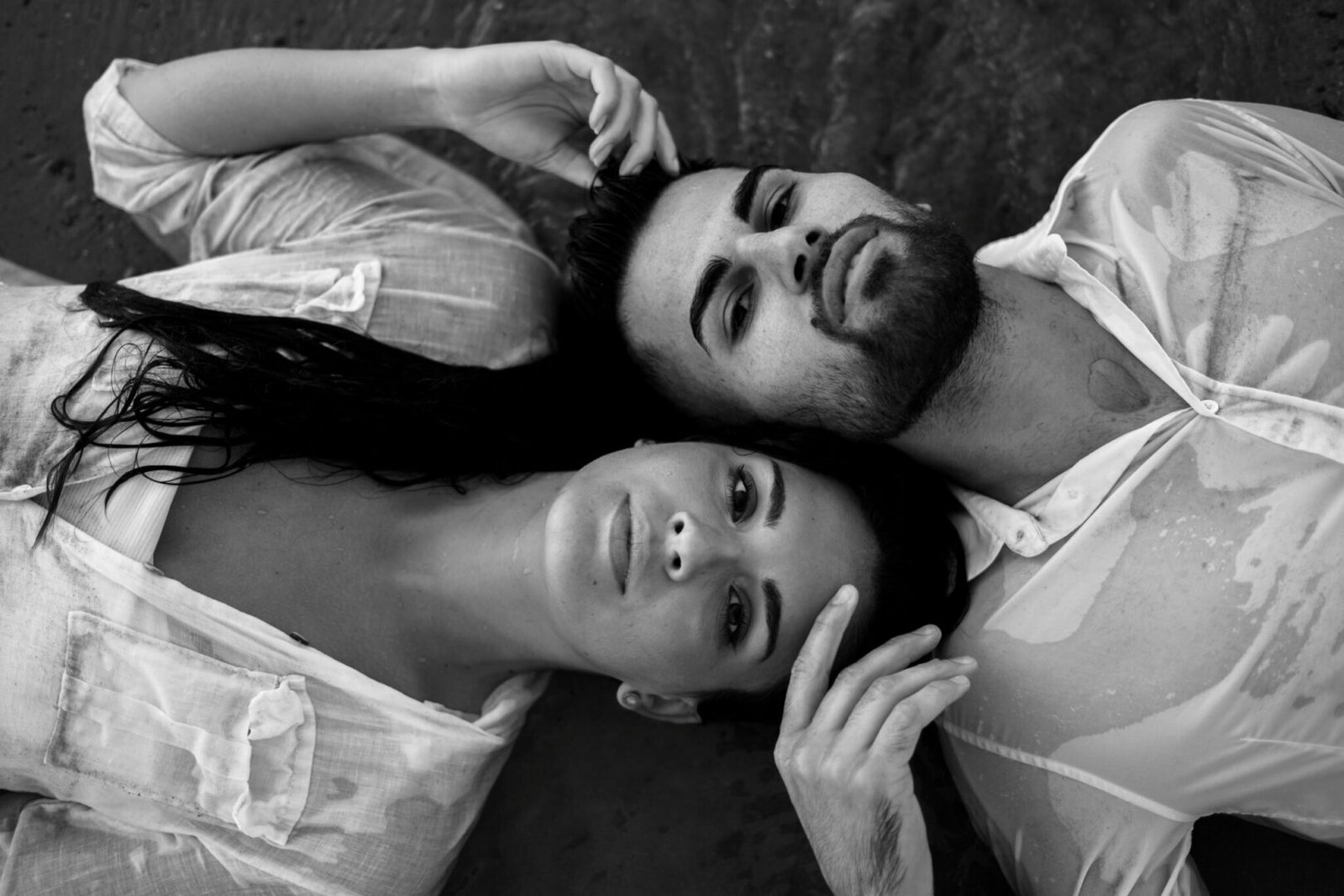 Portrait intimiste en noir et blanc d'un couple allongé pour une séance engagement